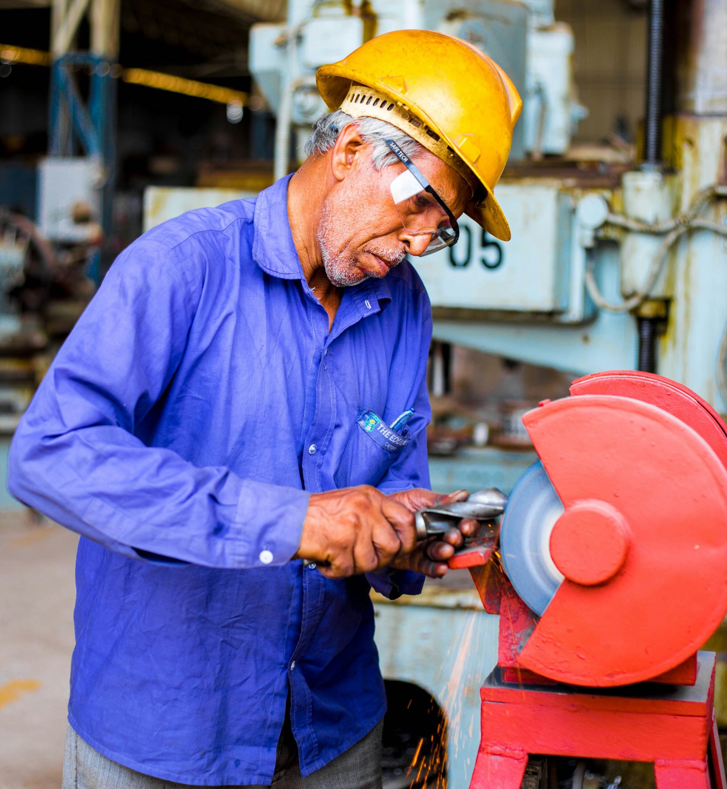 A worker uses machinery to sharpen an iron tool.